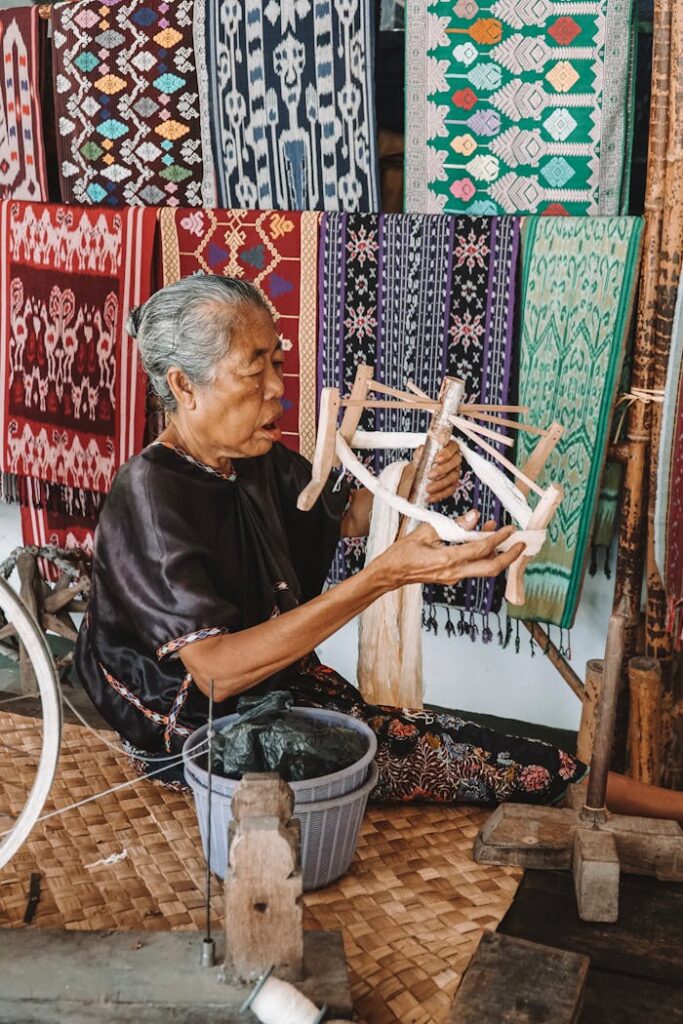 Elderly woman weaving traditional Indonesian fabrics, showcasing artisan craftsmanship.